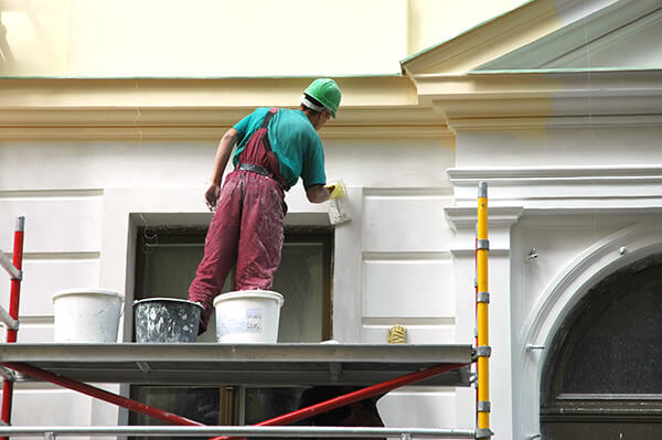 Worker is painting the exterior of a home.